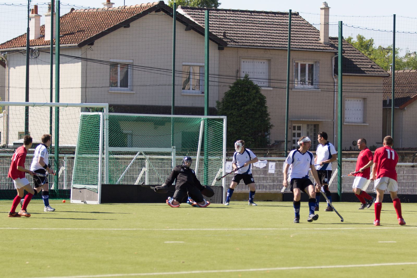 Le gardien du HSCSM plonge pour arrêter un tir devant son but, entouré de joueurs des deux équipes