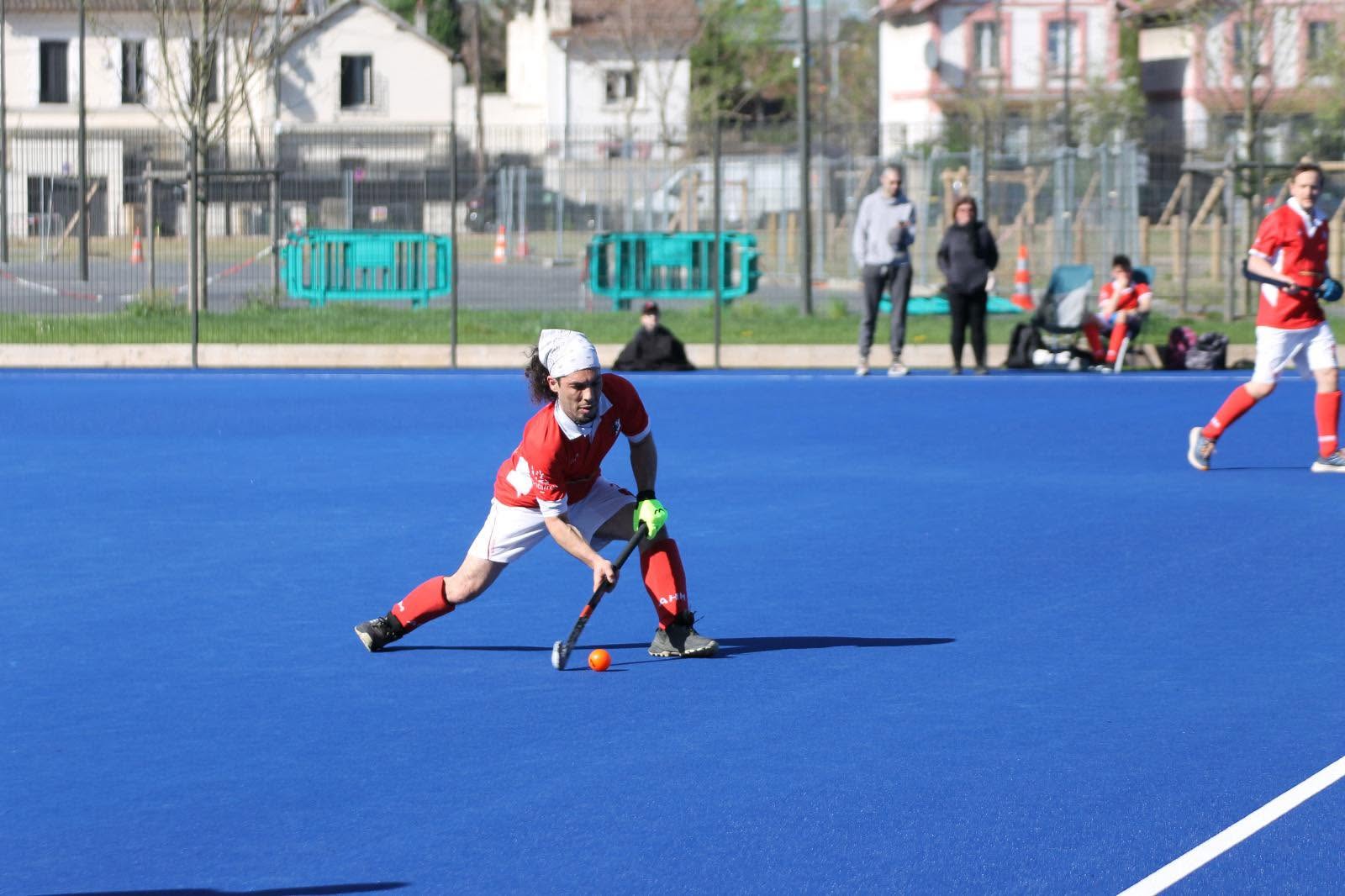 Joueur AHM en dribble sur terrain gazon synthétique bleu