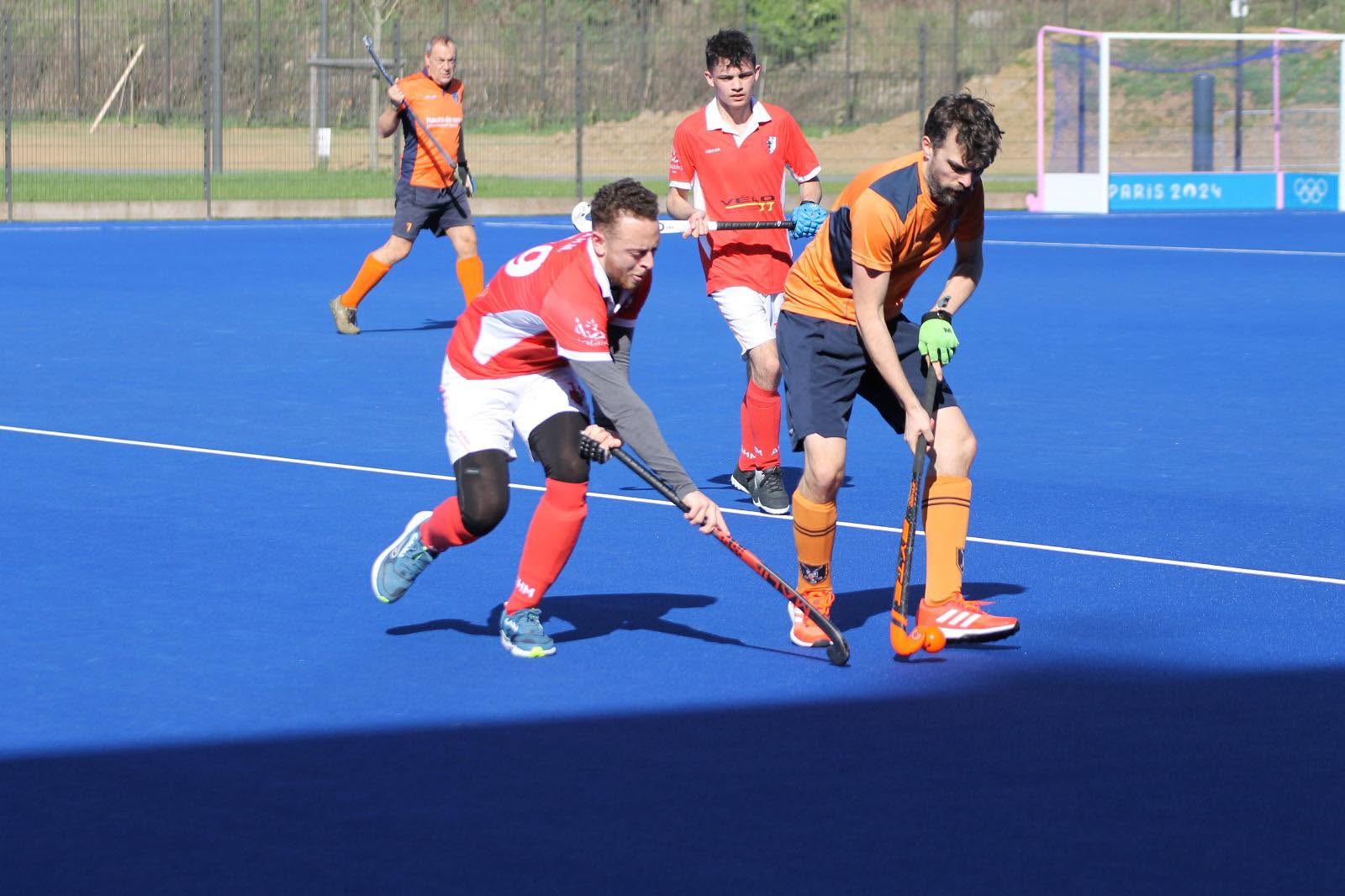 Duel entre joueurs AHM et adversaires sur terrain gazon synthétique bleu