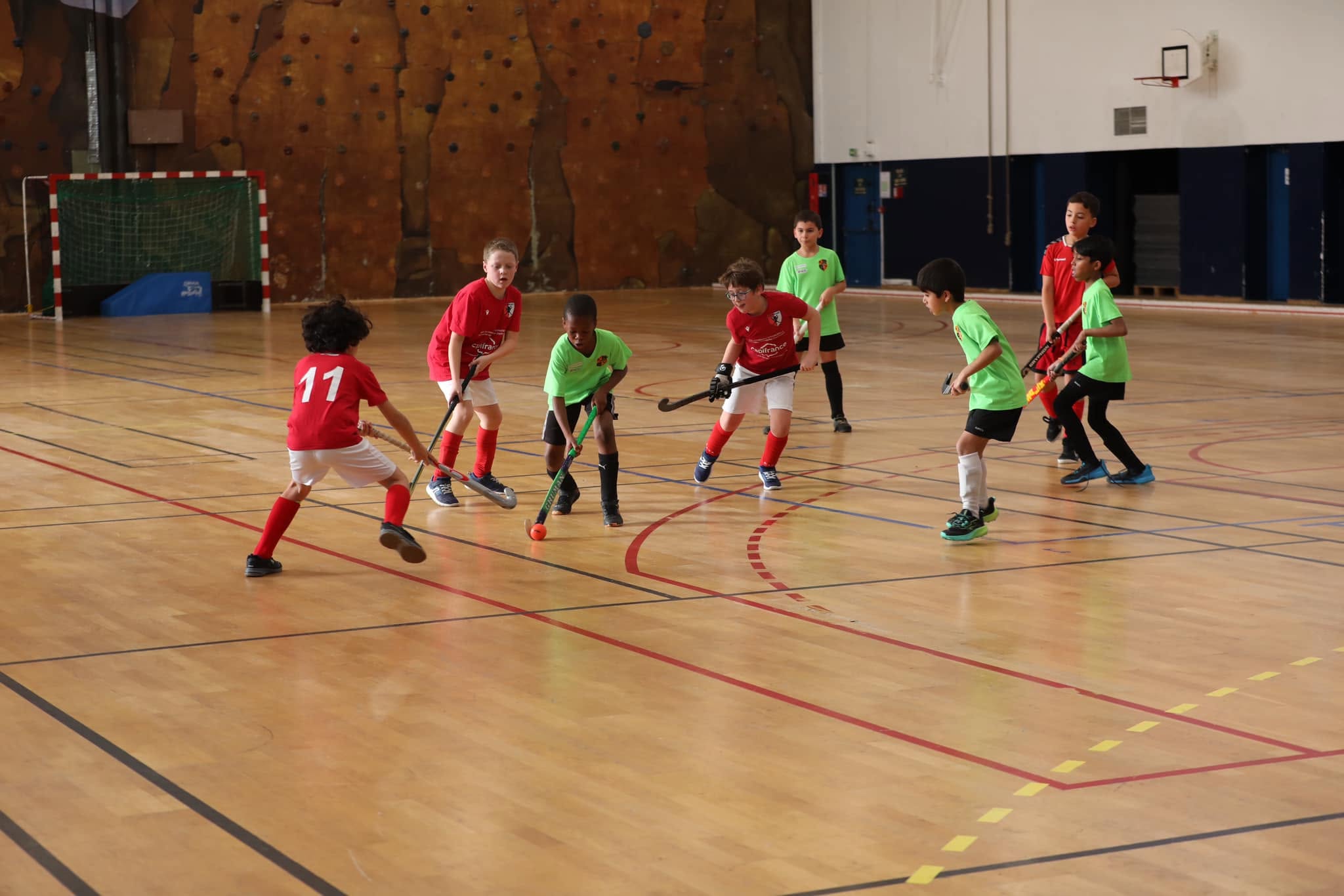 Vue d'ensemble d'un match de hockey en salle entre les jeunes AHM et une équipe verte